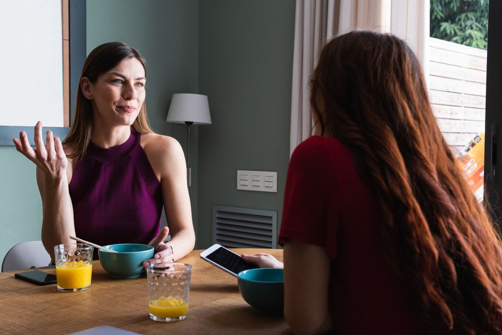 Happy women having lunch and browsing smartphone at home