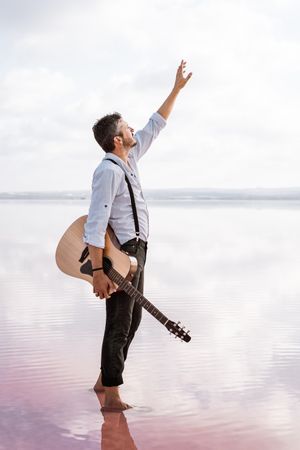 Inspired musician holding guitar at seaside