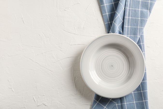 Kitchen towel with plate on neutral background, top view