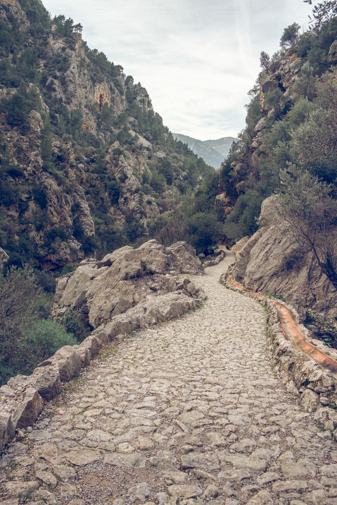 Cloudy sky over narrow stone path in mountainous valley