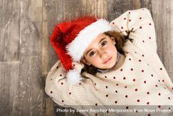 Girl in Santa hat lying on wooden floor 5QG9mb