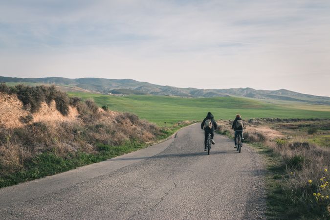 Men riding bicycles on road in desert hills