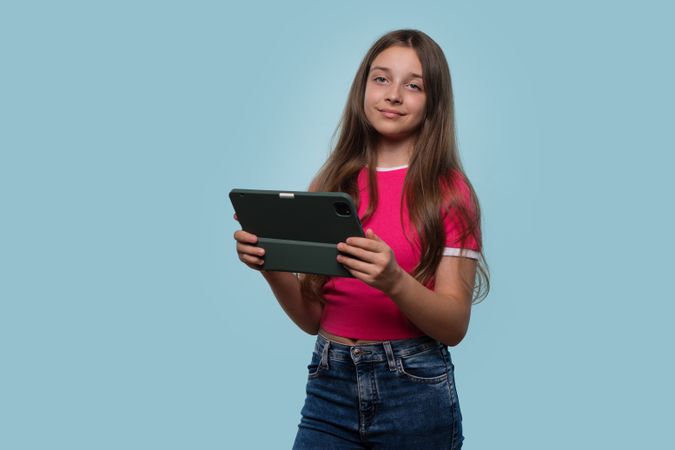 Young girl holds tablet with confident expression