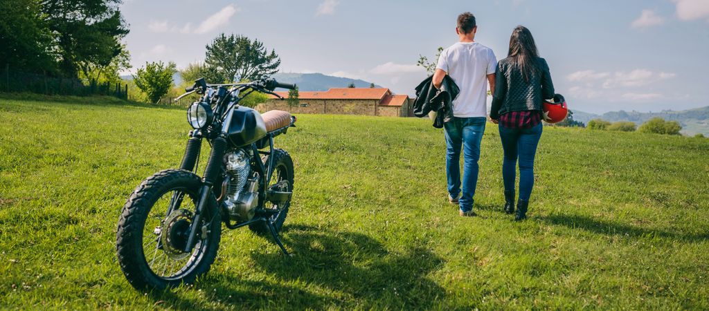 Couple walking on the field holding hands and motorbike