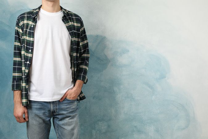 Men in t-shirt and checkered shirt against blue background, copy space