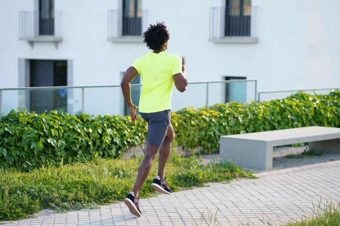 Black man exercising outside in neon shirt on walking path