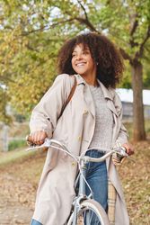 Smiling Black woman with bicycle in park