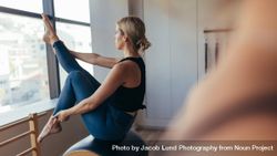 Woman sitting at the gym stretching her leg doing pilates workout 4BoKWb