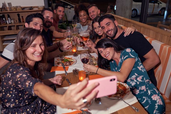 Cheerful diverse friends taking selfie in restaurant