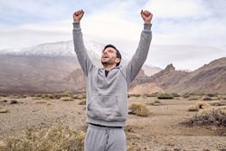 Happy man traveler raising hands and rejoicing achieving destination