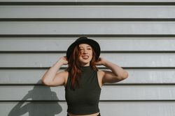 Smiling woman straightening hat and smiling looking along