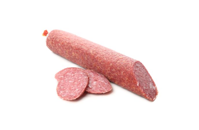 Salami stick with slices in plain room