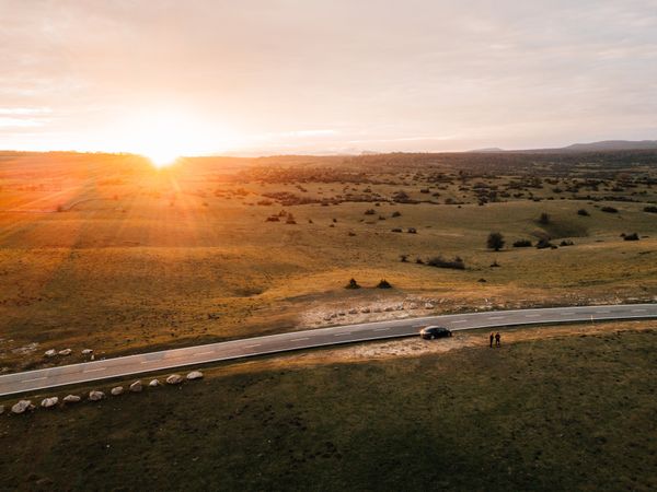 Bright sun setting over beautiful meadow and countryside road