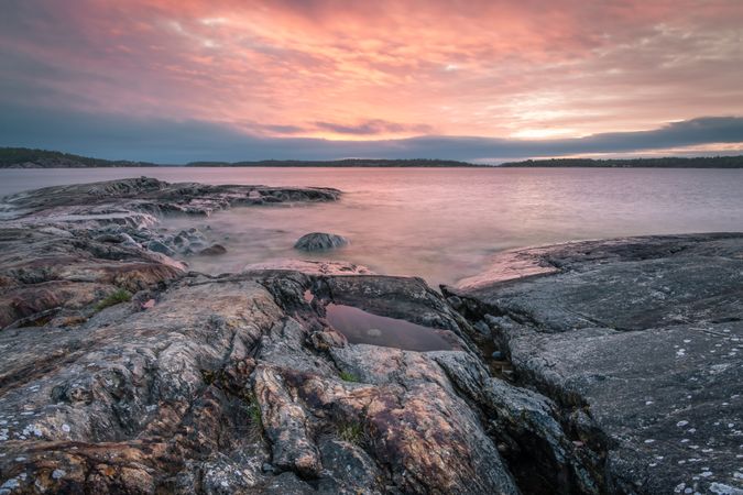 Gray rocky shore under cloudy sky during sunset