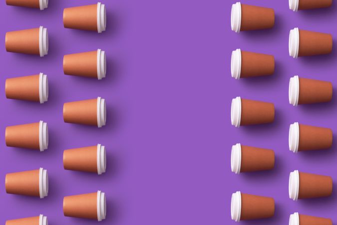 Disposable coffee cups on the sides on purple background
