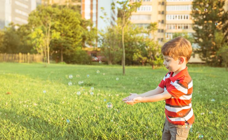 Happy boy playing with soap bubbles in the park