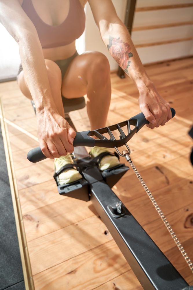 Crop female athlete doing workout on exercise machine