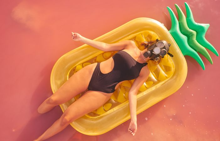 Woman lying on air mattress in pink lake water