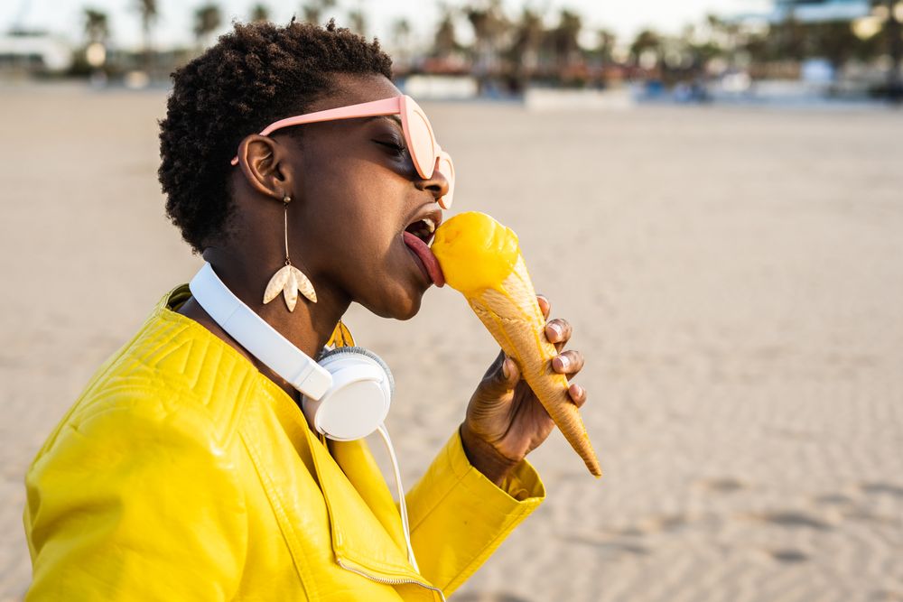 Cool female eating ice cream on beach