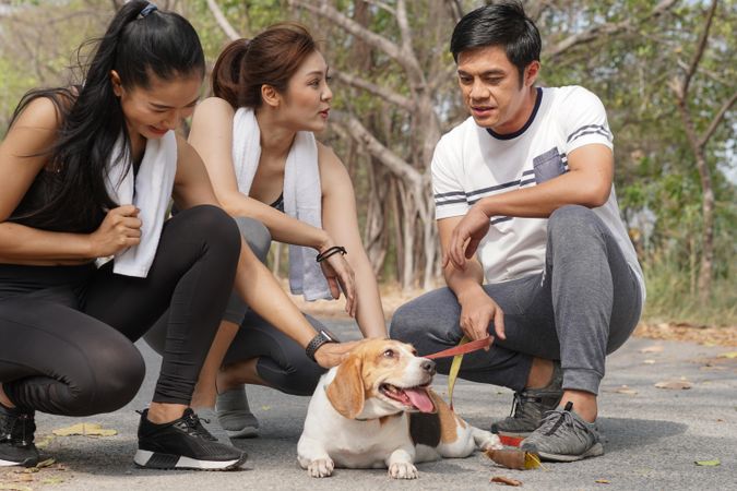 Two joggers stopping to chat with man walking cute dog