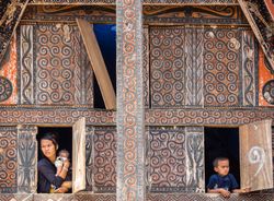 Bali, Indonesia - August, 15 2015: Mother with baby and kid looking out windows