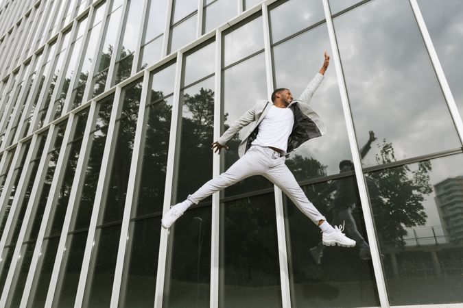 Enthusiastic Black man jumping raising hand like superhero