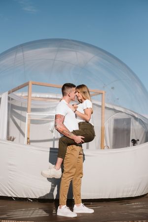 Affectionate couple kissing near bubble hotel