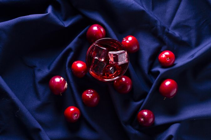 Red beverage near fresh fruits on cloth