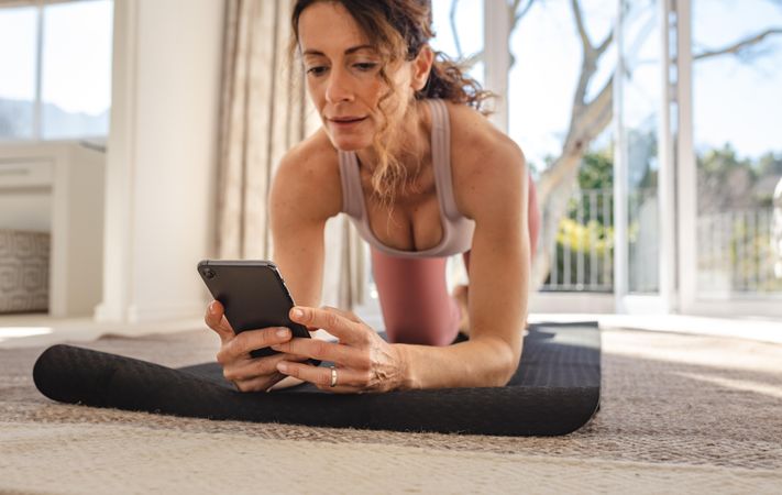 Woman looks in the phone online yoga lessons while exercising