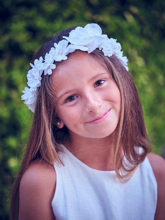 Charming girl in floral wreath and looking at camera