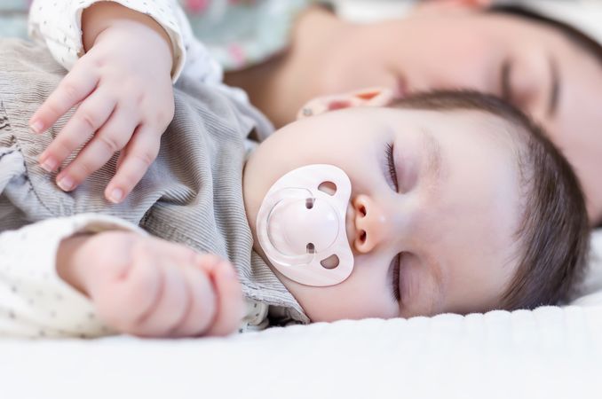 Young mother and her baby girl sleeping in the bed