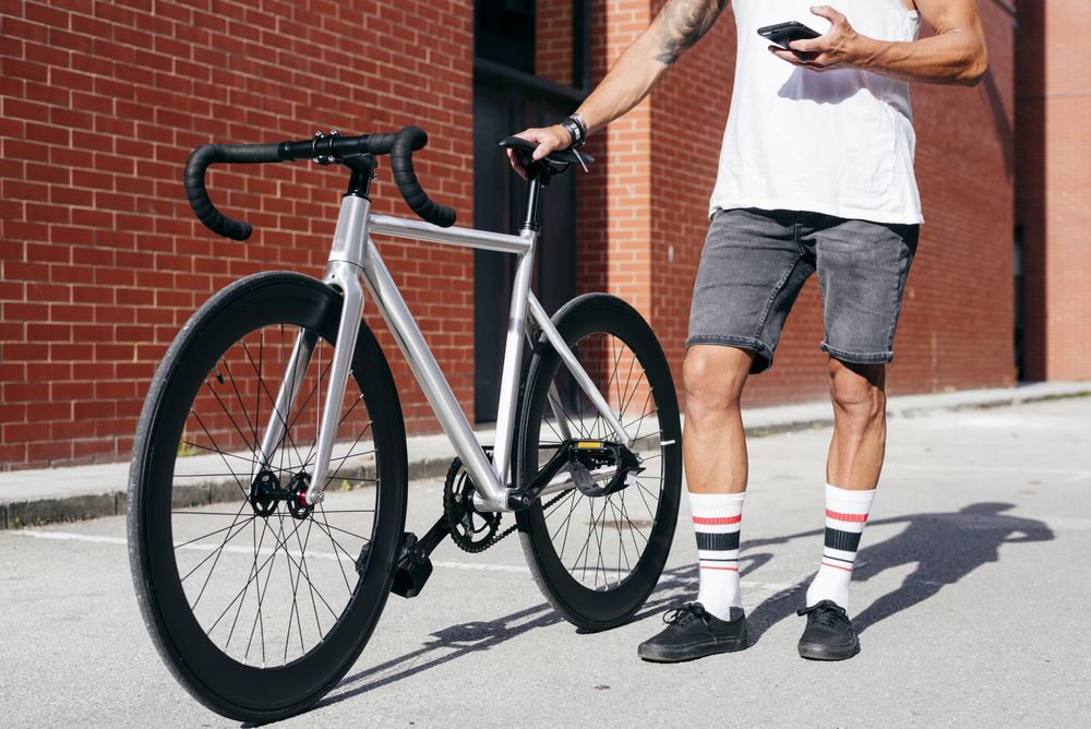 Sportive man with bicycle using phone