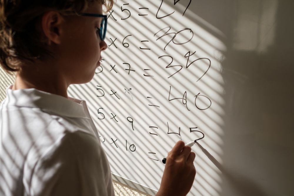 Diligent schoolboy near whiteboard during math lesson