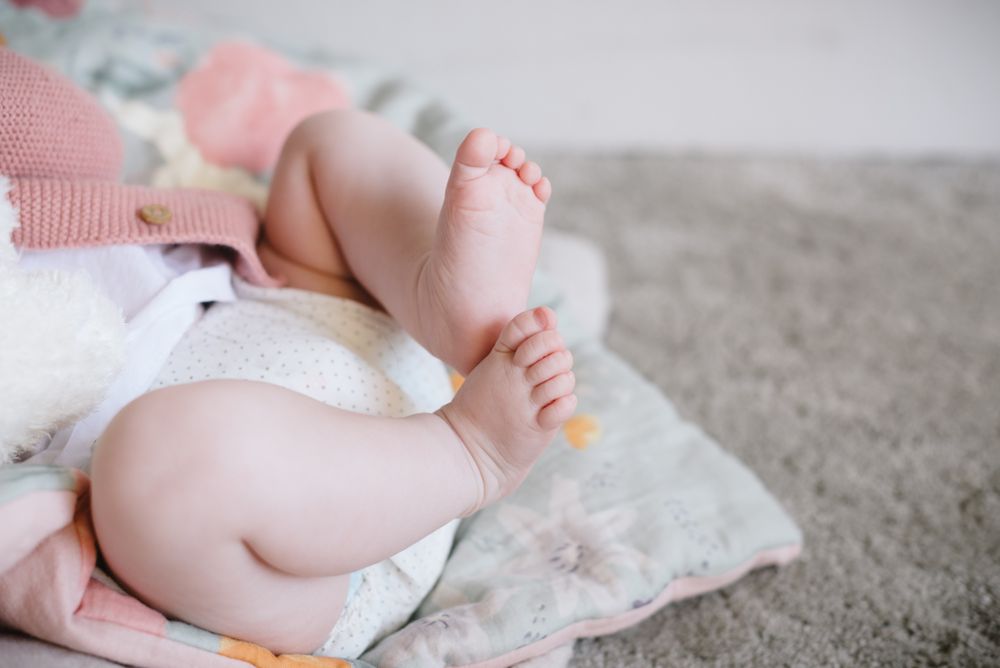 Cute baby lying and playing with plump legs