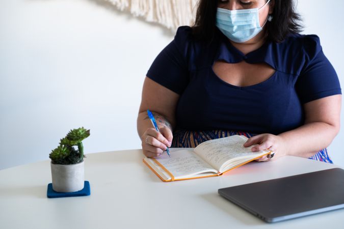 Woman in face mask writing in notebook