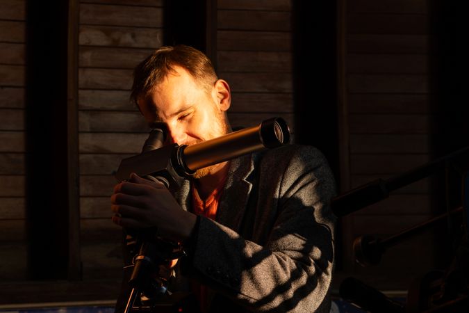 Man adjusts solar telescope while bathed in golden light.