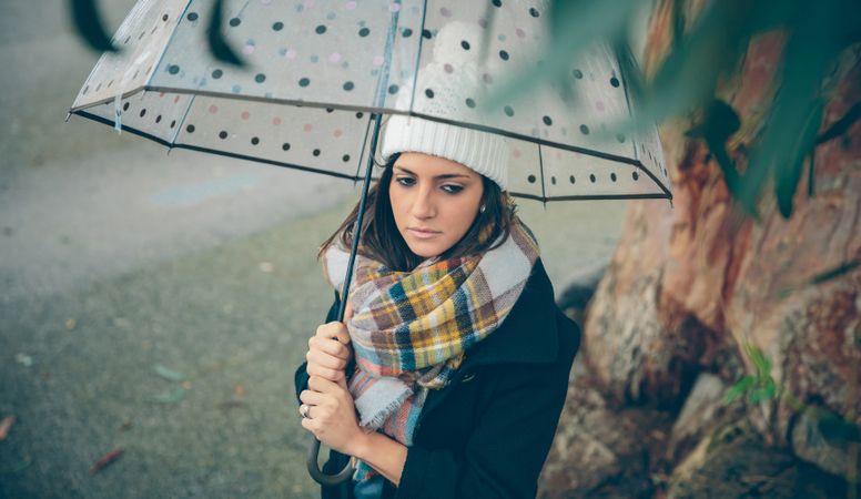 Woman deep in thought walking with umbrella on rainy day