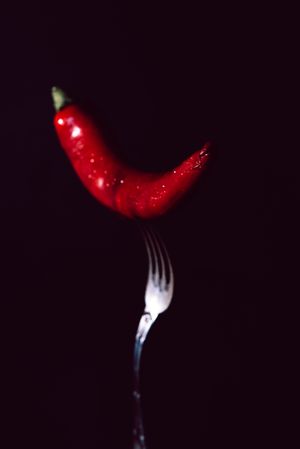 red chili pepper in fork on a dark background