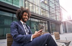 Joyful man in suit sitting outside and messaging