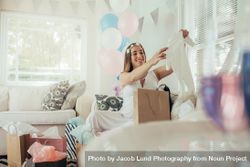 Pregnant woman opening a new gift after baby shower 5r9zw7