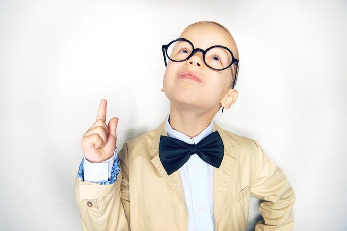 Blond boy pointing up in glasses with bow tie