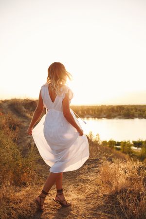 Blonde female in ethereal summer dress enjoying lake view