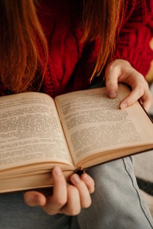Cropped image of woman in red sweater reading book