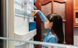 Sad girl taking the last yogurt from the fridge