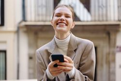 A Cheerful Woman Happily Using Her Smartphone While Enjoying the Outdoors in the City