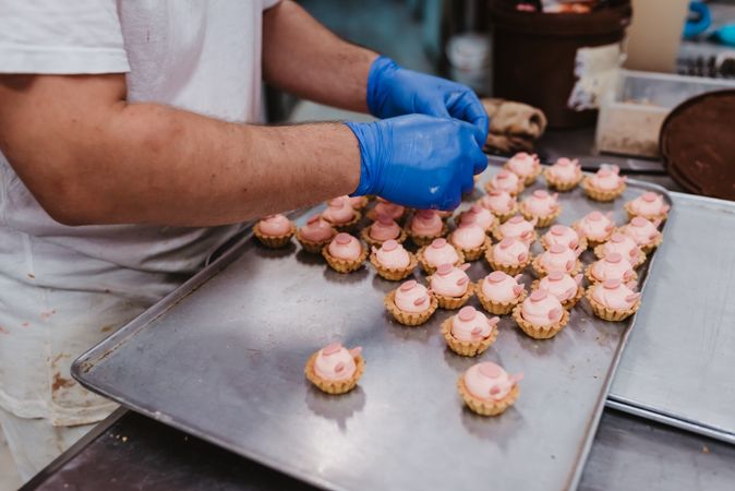 Anonymous baker decorating small cakes