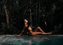 Side view of woman relaxing on side of beautiful private pool