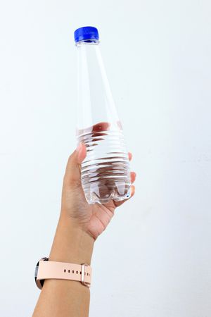 Female Hand with Pink Watch Strap Holding Mineral Water Bottle
