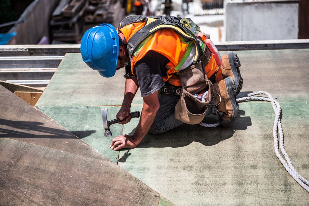 Man in bump cap chiding a nail to the floor