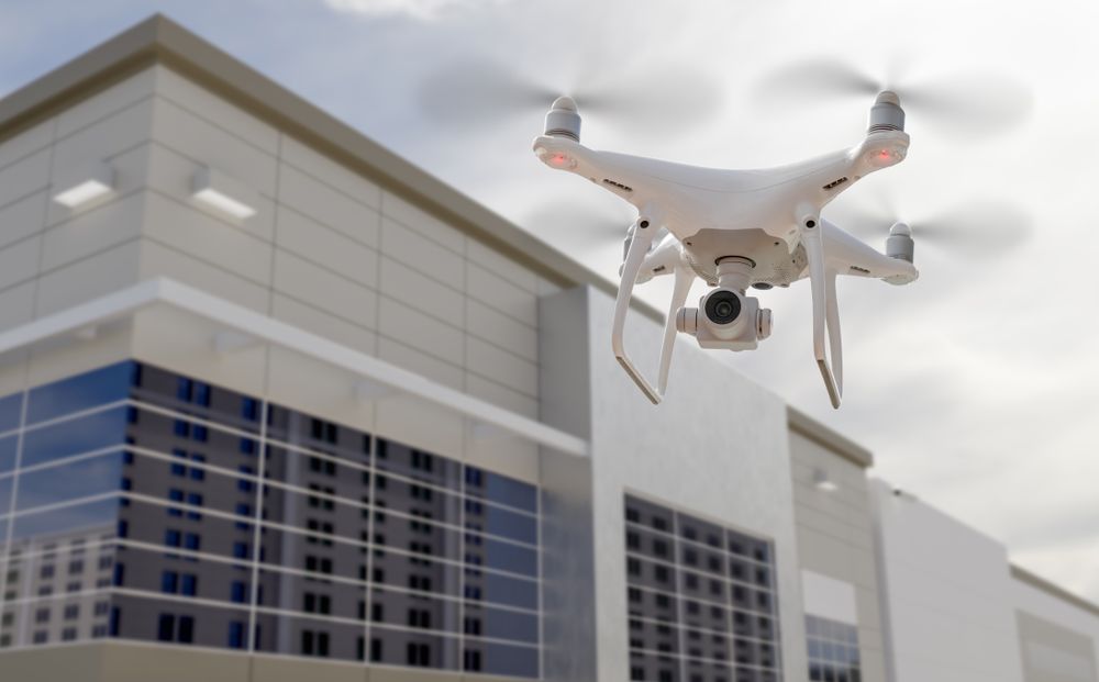 Unmanned Aircraft System Quadcopter Drone UAV In The Air Near Corporate Industrial Building